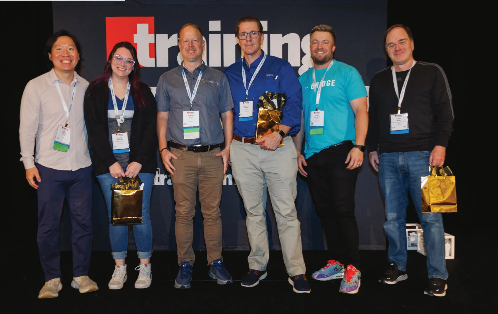 Winners of the sponsor drawings, holding gold prize bags, from left, Amelia Rutledge (Fidelity Investments), Richard Hannah (HASC), and Sean Neely (LEG-TECH) with sponsor reps, from left, WellSaid’s Billy Sheng, Intellezy’s Andrew Black, and Bridge’s Tyler Gossard. Prizes included an iPad Mini, Beats Headphones, and a $500 Visa gift card.