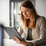 AI Adoption: Building AI That Empowers Teams a young woman typing on her ipad.