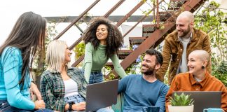 group of young diverse students sitting together in a room filled with plants.