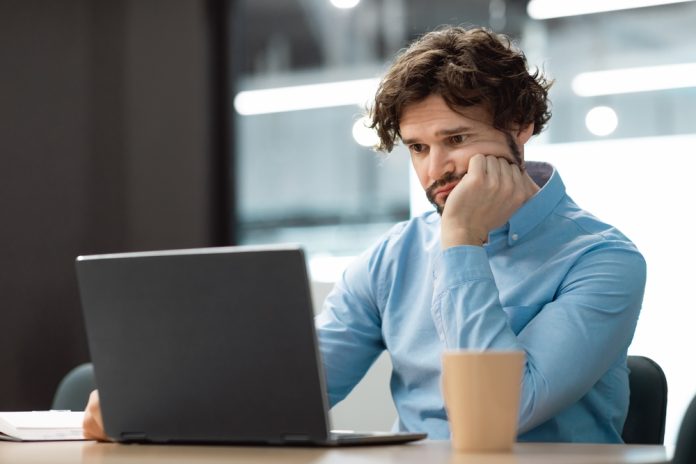 Portrait,Of,Sad,Bored,Business,Man,Sitting,At,Desk,Using