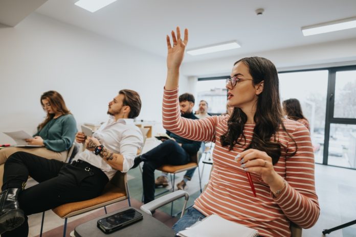 Focused,Young,Woman,With,Glasses,Raising,Her,Hand,In,A