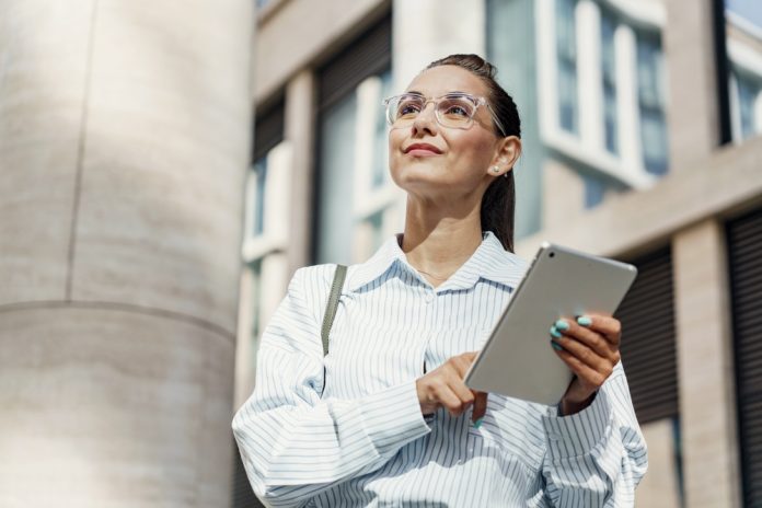 A,Visionary,Businesswoman,Holds,Her,Tablet,With,Poise,,Gazing,Forward