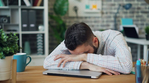 Man with his head down on his desk
