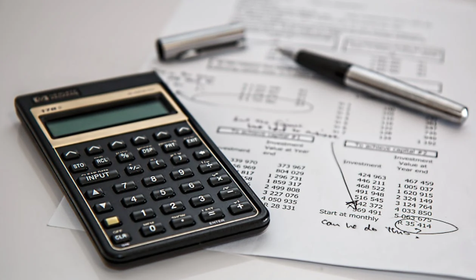 Accounting Training a picture of a desk with a calculator and a sheet and pen.